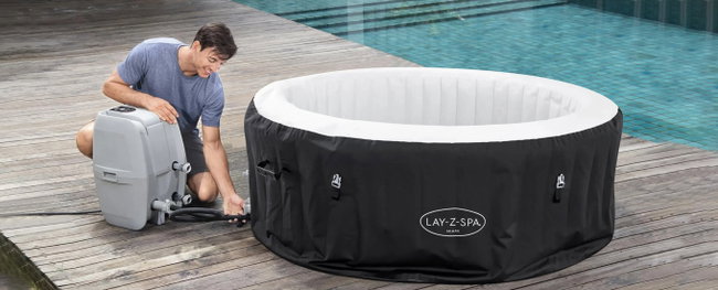 poolplatz.de-blog-aufblasbarer-whirlpool mann schliesst pumpe an whirlpool an