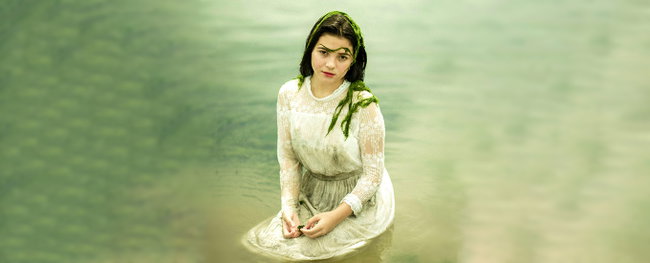 frau in weißem kleid sitst im wasser, bedeckt mit algen